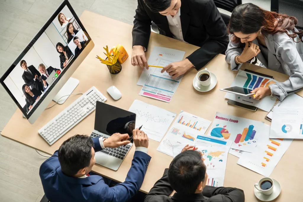 Boardroom meeting with four people and several people on a conference call.